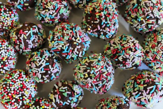 Bâtonnets au chocolat recouverts de vermicelles colorés sur un plateau.